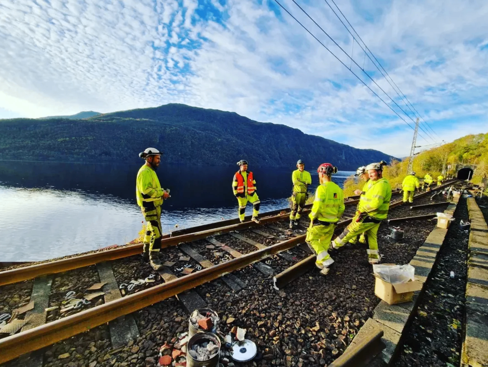 Arbeidslag langs jernbanespor ved fjord og tunnel